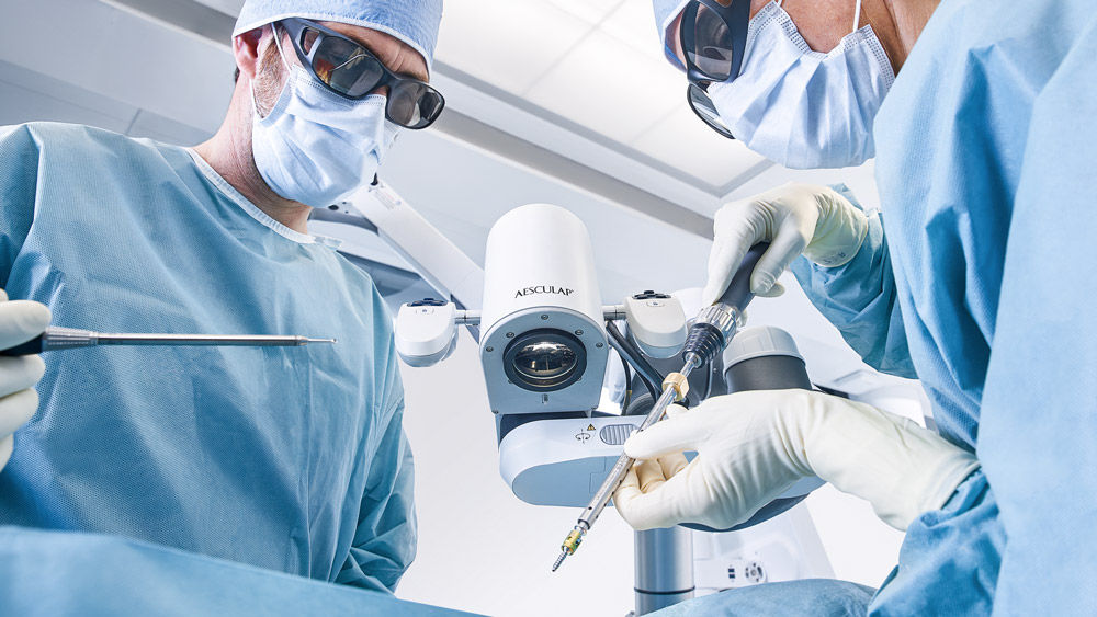 Chirurgiens au bloc opératoire avec un microscope chirurgical assisté par robot