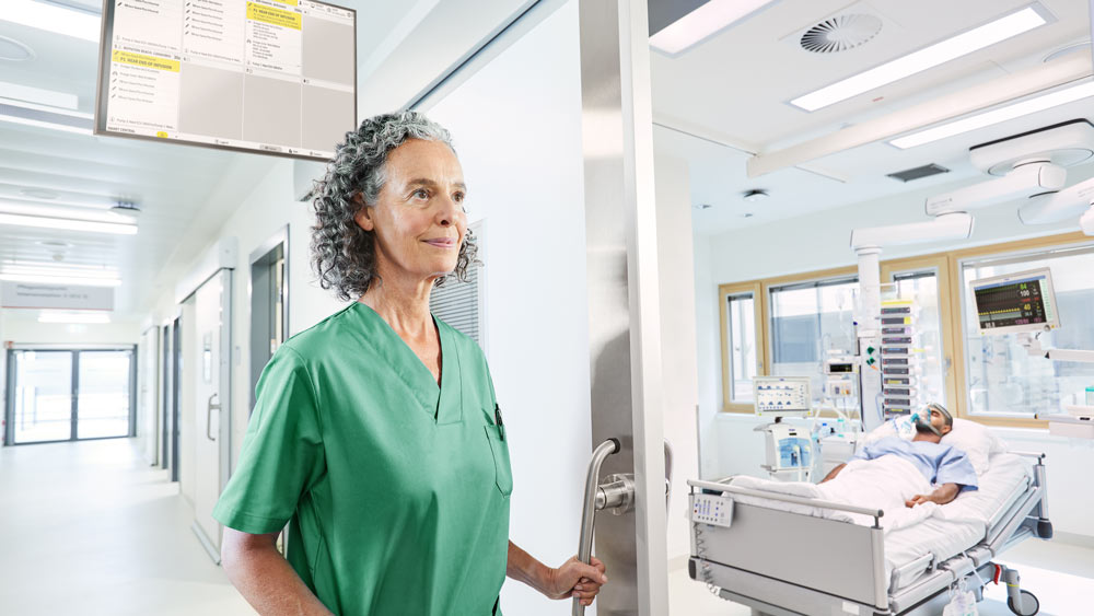 L’infirmière entre dans la chambre du patient en unité de soins intensifs avec une gestion prioritaire des alarmes